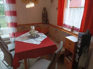 A dining area with a table set for two, a bench, and a window with curtains. - SONBERG House - near the ÖBB Weststeiermark Train Station - free bikes (Groß Sankt Florian)