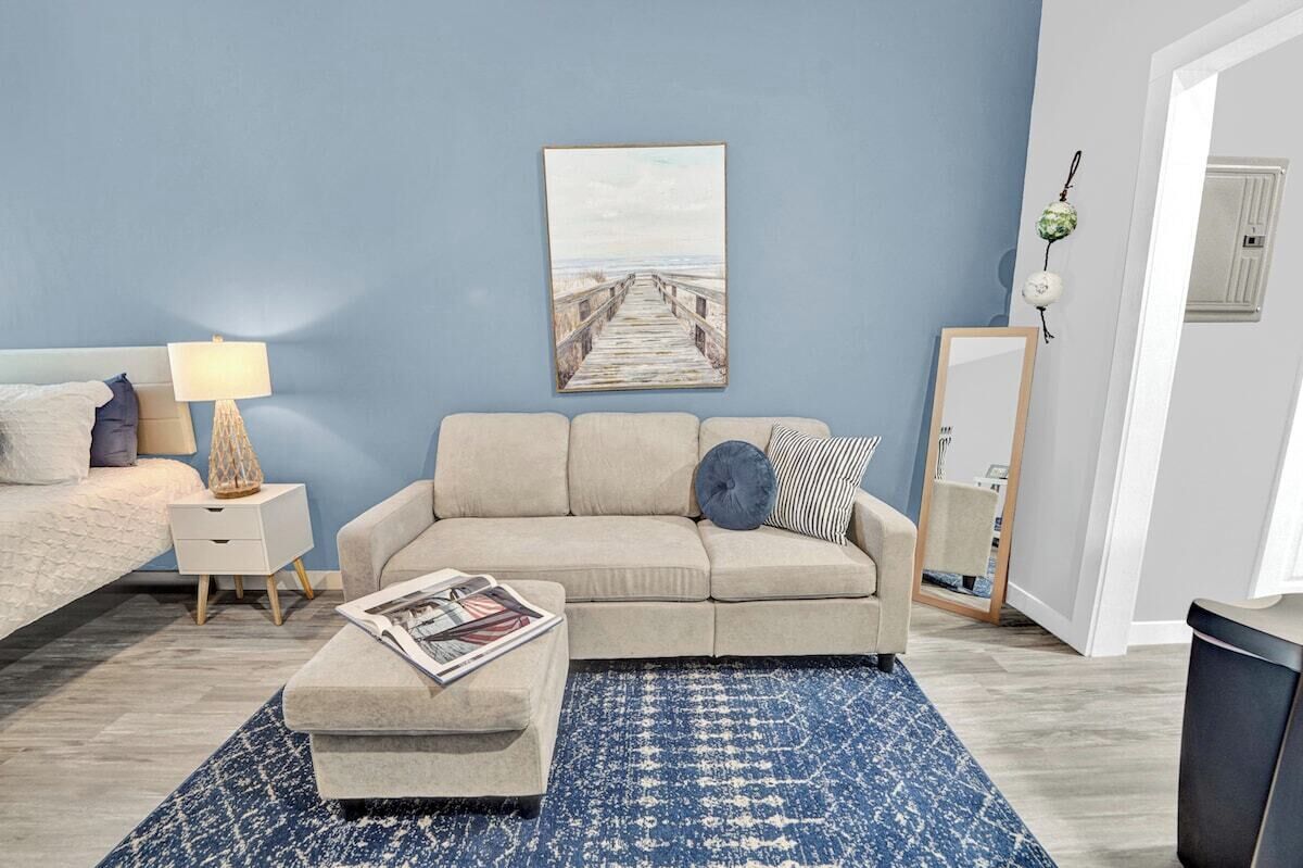Et soveværelse med seng, natbord, lampe, sofa, sofabord og et maleri på væggen.