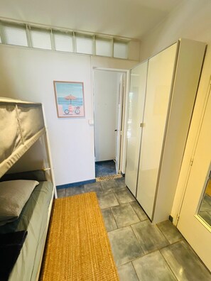 A narrow hallway with a bunk bed on the left, a door on the right, and a small rug on the floor. - Giens Peninsula - ocean view - direct access to the beach - La Bergerie - La Capte (Hyères)