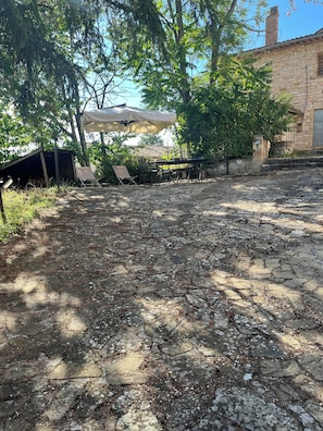 A courtyard with stone flooring, outdoor seating, and a covered area. - Monti Sibillini House: A Stone House in the Monti Sibillini National Park (Marche)