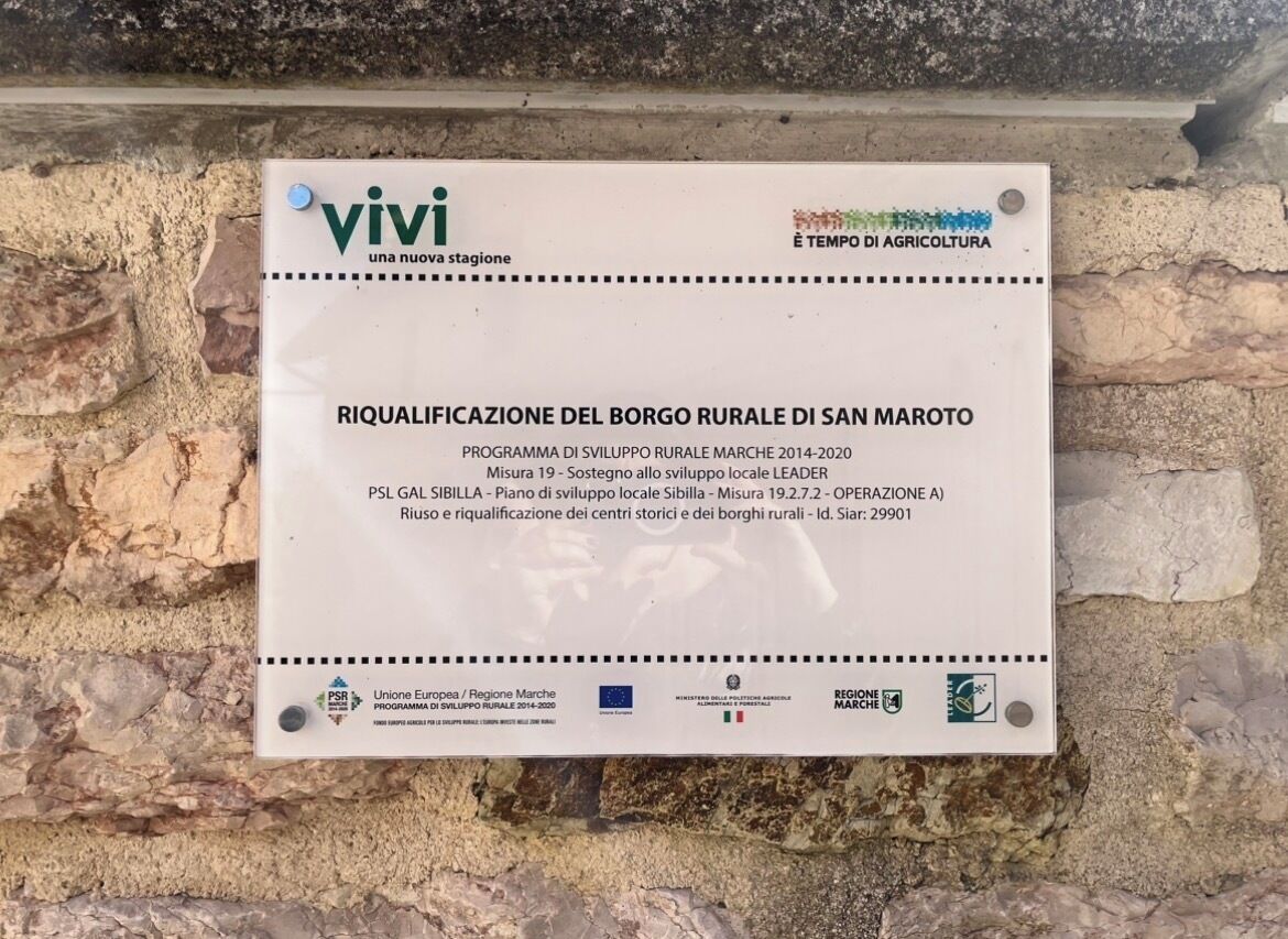 A sign mounted on a stone wall.