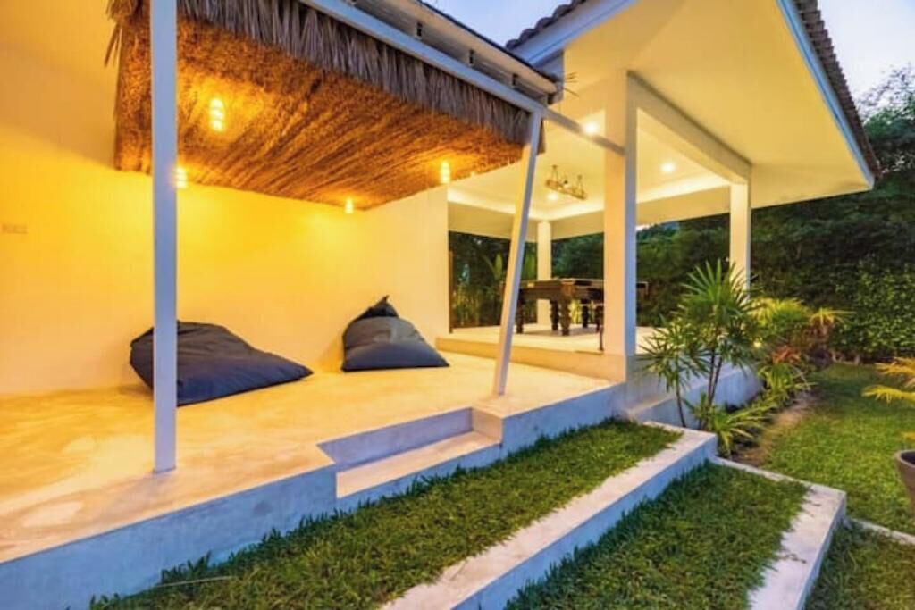 Uma casa moderna com varanda coberta, área de refeições e jardim.