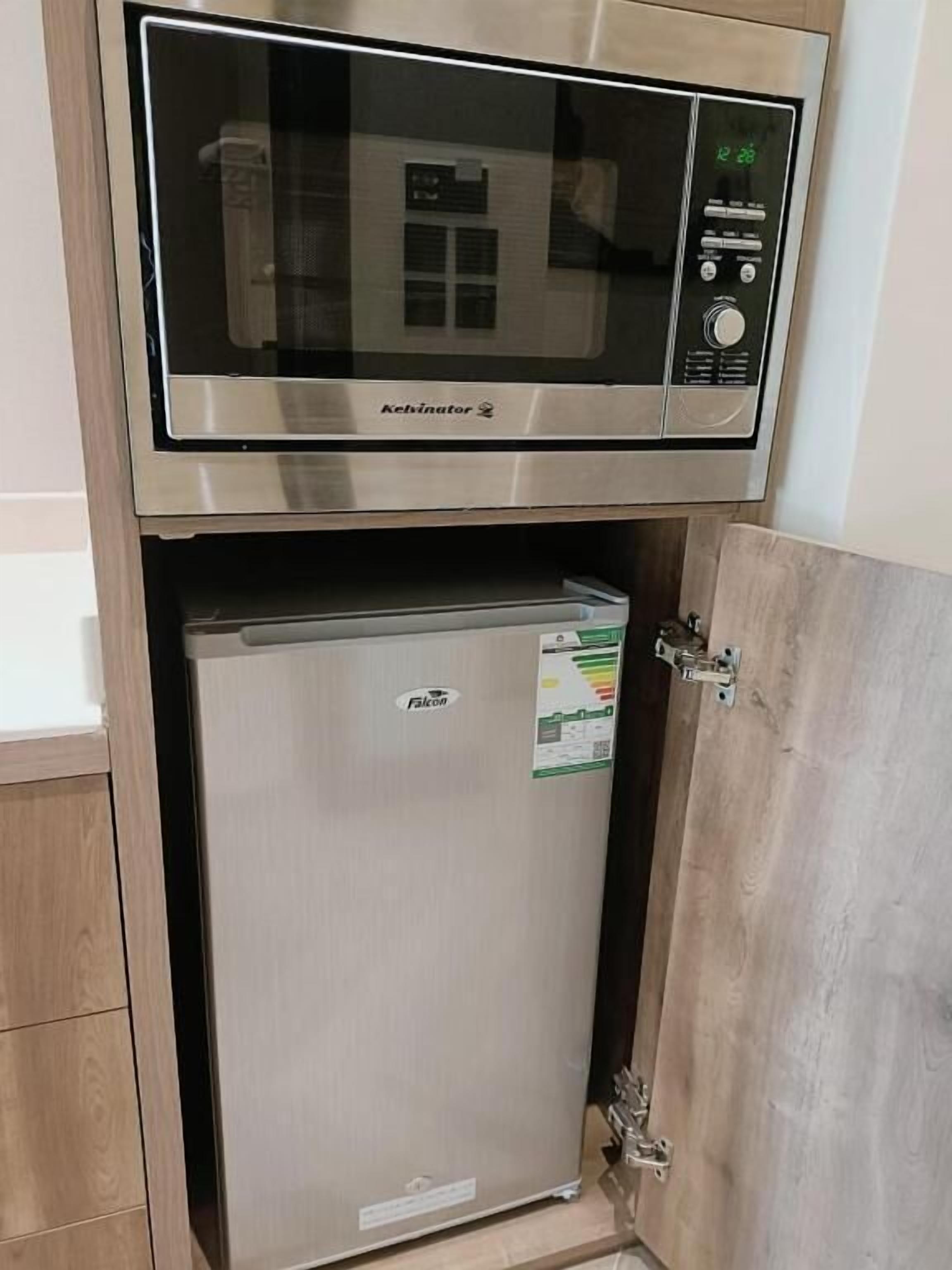 Eine kleine Küche mit integriertem Mikrowellenherd und Kühlschrank.