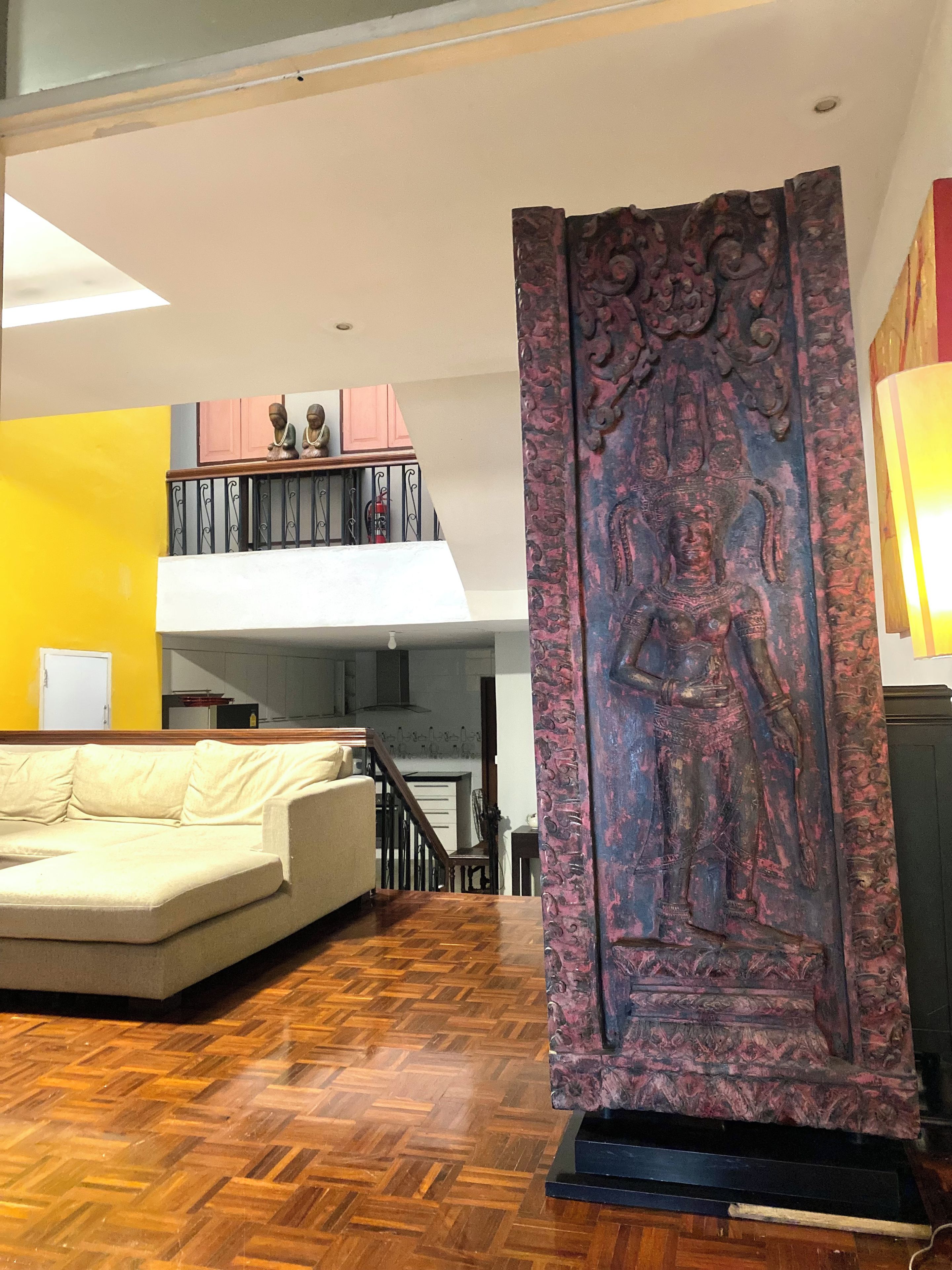 Sala de estar com sofá, painel decorativo e escada.