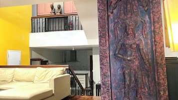 Sala de estar com sofá, painel decorativo e escada.