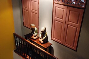 Una escalera con barandilla, una mesa de madera con dos figuritas y una pared con dos puertas de madera.