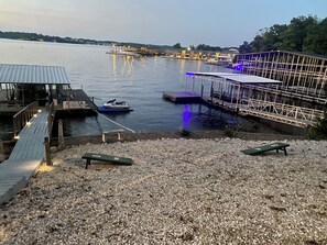 Ein Uferbereich mit einer Mole, einem Jetski, einem überdachten Weg und einem Kiesstrand.