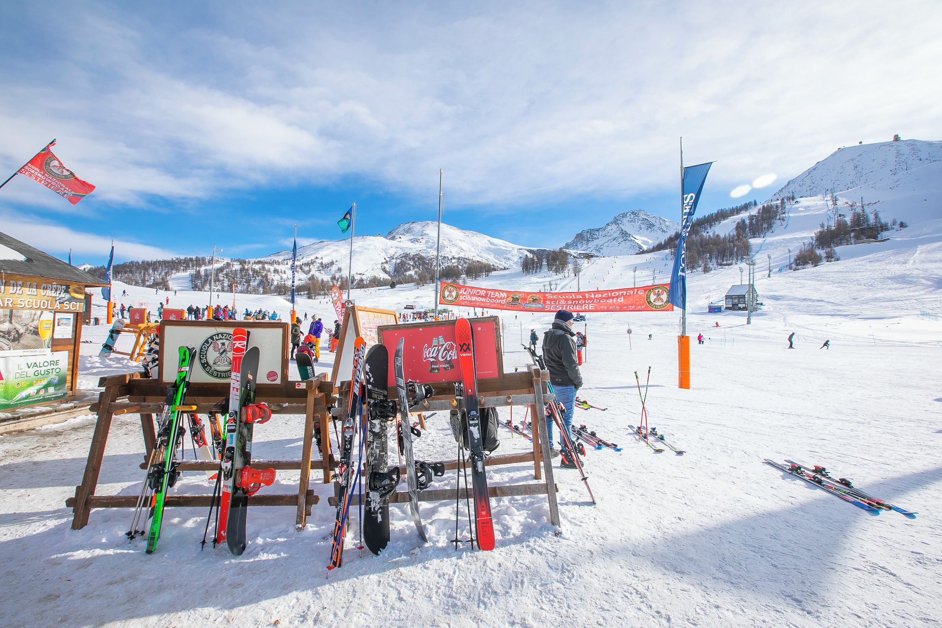 A ski resort with a wooden ski rack holding various skis and snowboards.