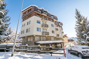 Un hotel de varios pisos con balcones, una zona de estar techada al aire libre y un paisaje nevado.