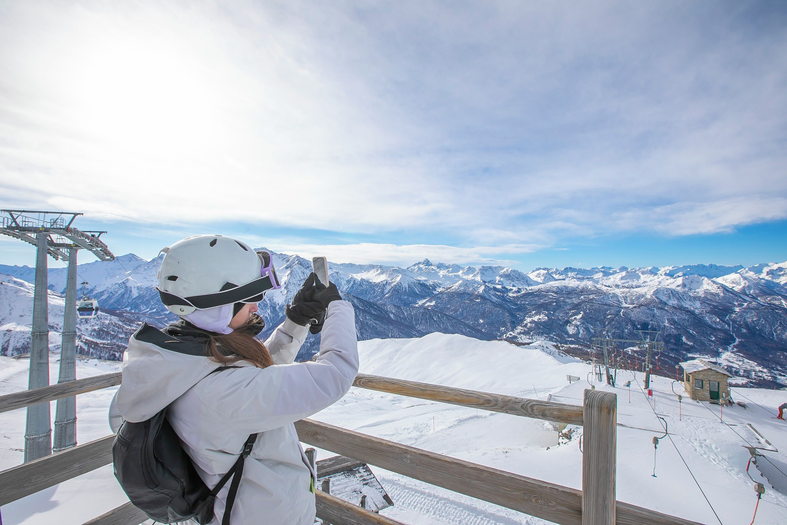 A person taking a photo from a ski lift with a view of snow-covered mountains.