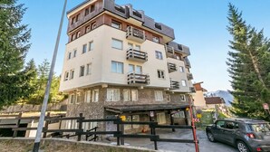 A multi-story building with balconies, a covered entrance, and a mountain view. - Gran Roc 9 (Sestriere)