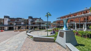 Una plaza pública con una fuente, zonas de descanso y un edificio de fachada de vidrio.