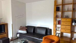 Ein modernes Wohnzimmer mit Ledersofa, Glastisch und Bücherregal.