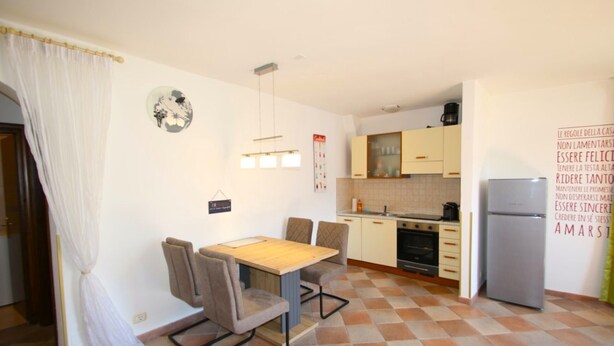 A compact kitchen with a dining area, a refrigerator, and a wall with motivational text. - Arias Giovanna Visa Lago Villa (Tremosine)
