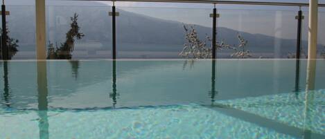Une piscine intérieure à l’eau claire, entourée de murs en verre.