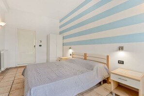 Ein Schlafzimmer mit Bett, Nachttischen, einem Kleiderschrank und einer gestreiften Wand.