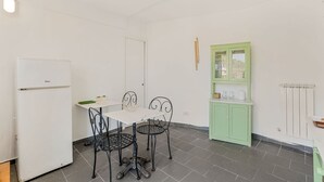 Et lille køkken med et hvidt køleskab, et spisebord med fire stole og et grønt skab.