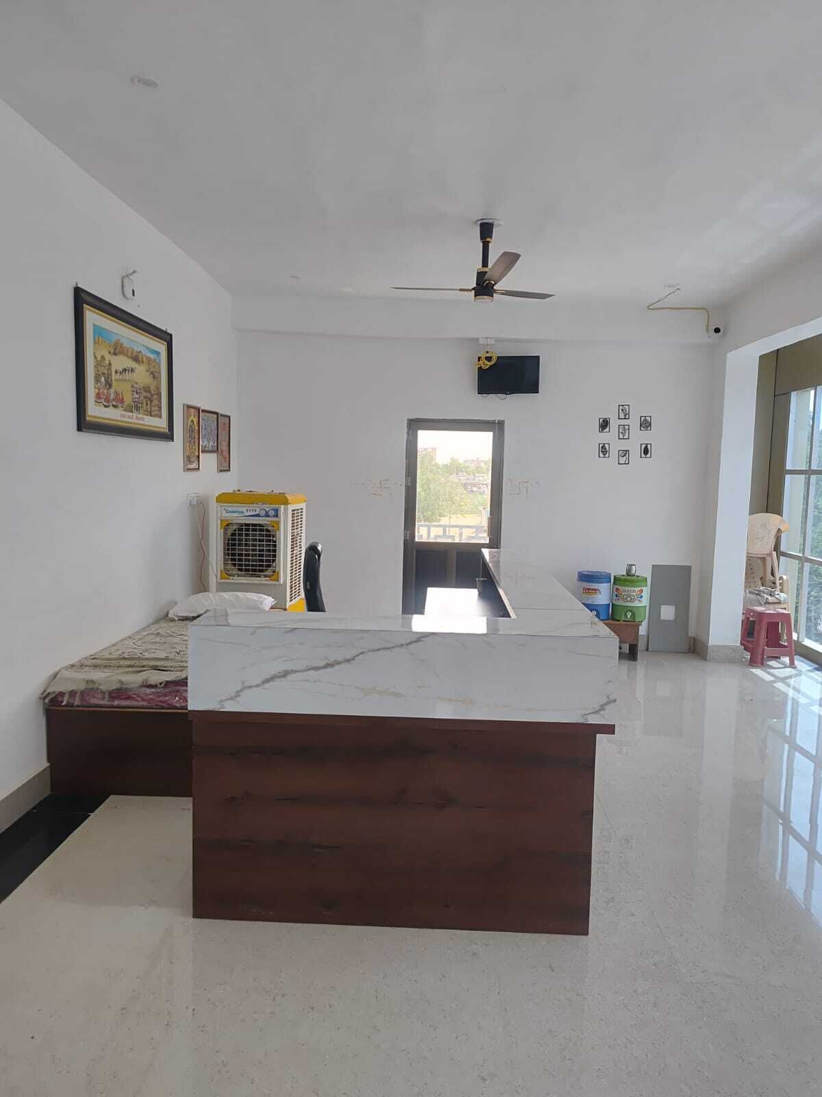 A room with a bed, a desk, a ceiling fan, and a window.