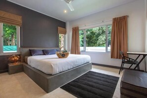 Un dormitorio moderno con una cama grande, una mesita de noche con lámpara, una ventana con cortinas y vistas a la vegetación.