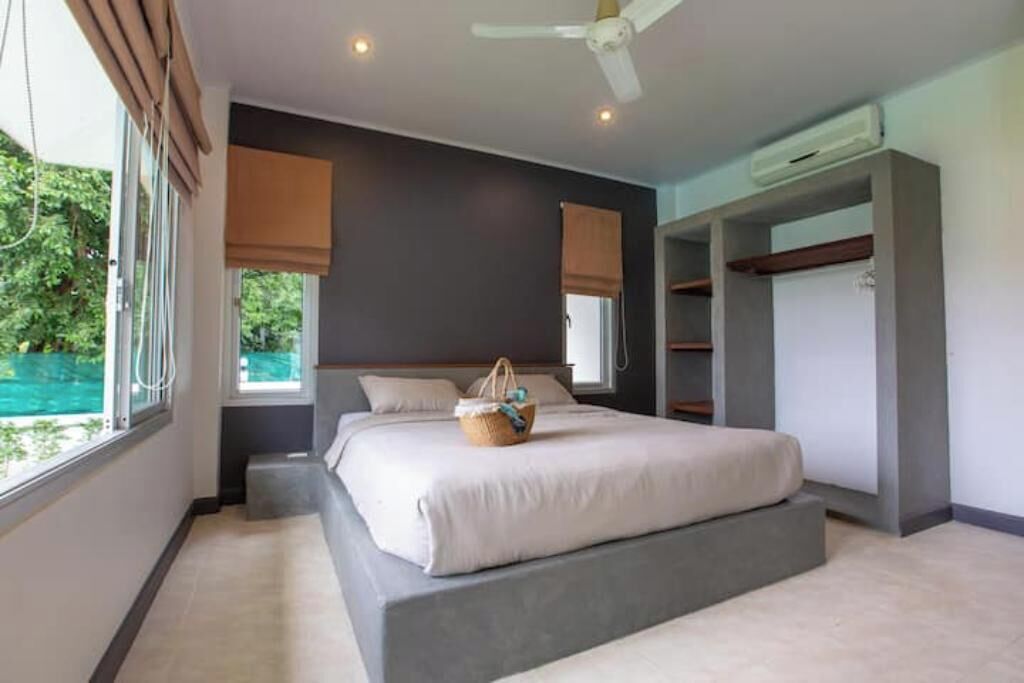 Ein modernes Schlafzimmer mit einem Bett, einem Deckenventilator und einem Fenster mit Jalousien.
