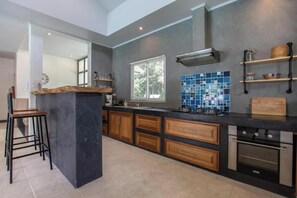 Eine moderne Küche mit Kochinsel, Holzschränken und integriertem Backofen.