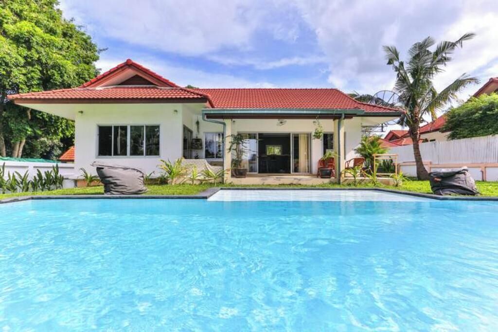 A two-story house with a swimming pool in front.