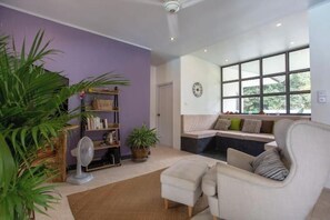 A living room with a sofa, a fan, and a bookshelf. - 2 bedrooms pool villa in peaceful garden (Koh Samui)