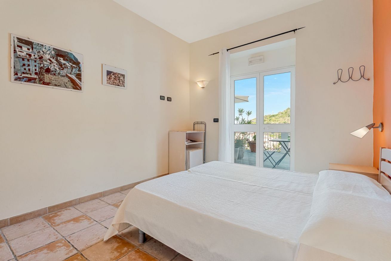 Une chambre à coucher comprenant un lit, une petite armoire, une fenêtre avec vue et des œuvres d’art accrochées au mur.