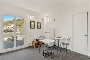 Ein Zimmer mit Essbereich, einem weißen Kühlschrank und Blick durch eine Glastür.
