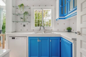 Eine Küche mit weißer Arbeitsplatte, einem Spülbecken und blauen Schränken.