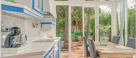 Una cocina moderna con gabinetes azules, una estufa integrada y un comedor con mesa y sillas.