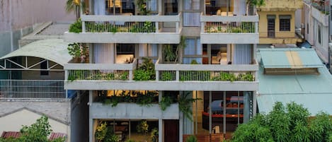Um edifício com várias andares e varandas decoradas com plantas.