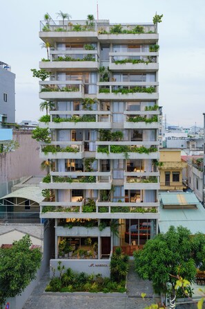 Um edifício com várias andares e varandas decoradas com plantas.