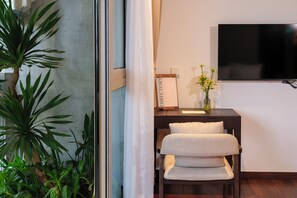 A hotel room with a desk, a chair, a television, a plant, and a sign that reads 'DIRECTORY'. - Marisol Hotel (Da Nang)