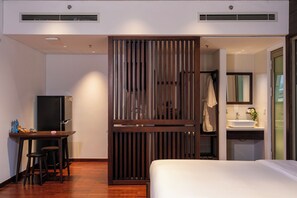 A hotel room with a bed, a desk with a chair, a television, and a bathroom with a sink and mirror. - Marisol Hotel (Da Nang)