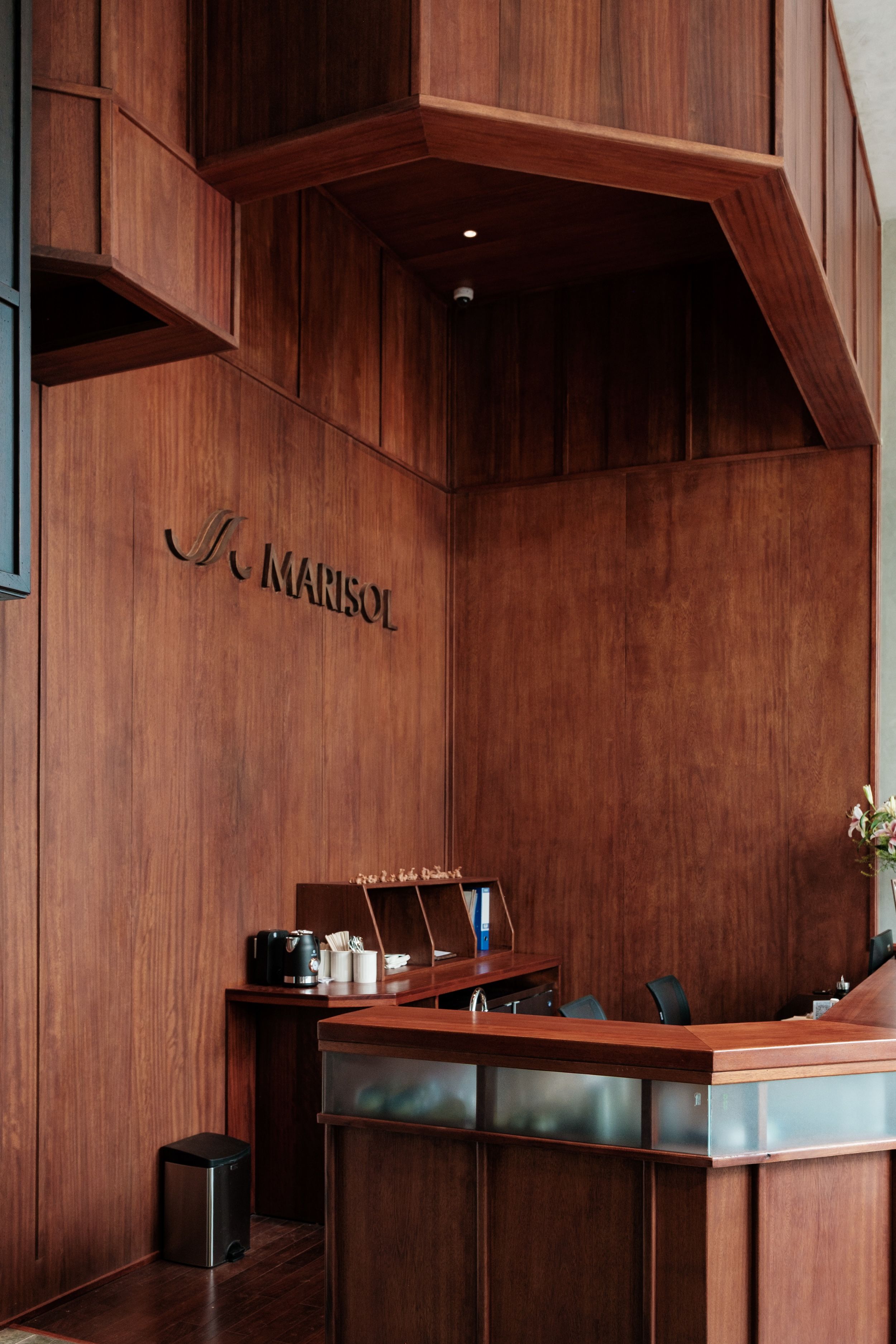 A reception desk with a wooden finish, a coffee machine, and a trash bin.