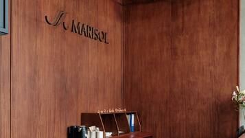 A reception desk with a wooden finish, a coffee machine, and a trash bin.