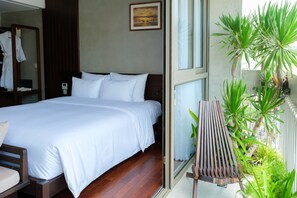 A hotel room with a bed, a wooden bench, and a view of the outside. - Marisol Hotel (Da Nang)