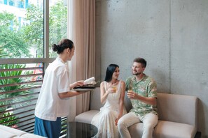 A hotel room with a large window, a sofa, and a table. - Marisol Hotel (Da Nang)