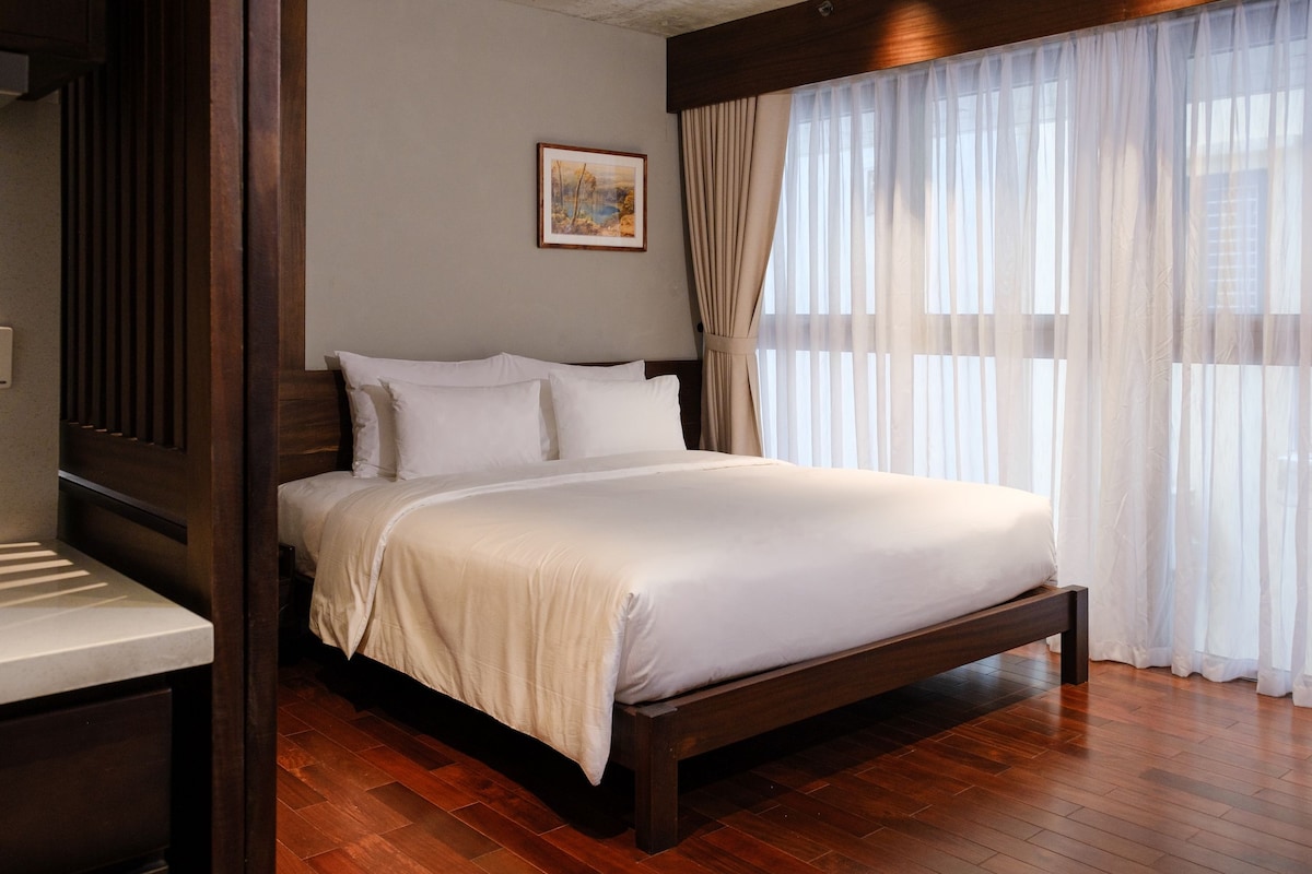 Un lit bien fait, avec une tête de lit en bois, dans une chambre d’hôtel.