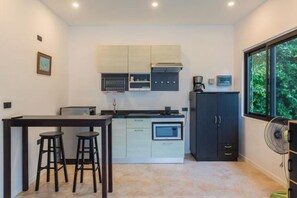 A compact kitchen with a dining area, a built-in oven, and a window providing a view of greenery. - 3 bedrooms villa (Koh Samui)