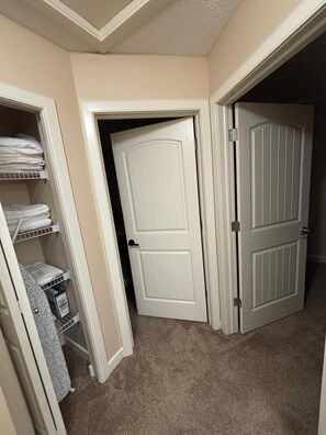 A hallway with two closed doors, a closet with folded towels, and a patterned rug. - Modern townhouse  offers the ideal blend of convenience and comfort, (Edmonton)