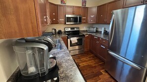 A kitchen with wooden cabinets, stainless steel appliances, a coffee maker, and a blender on the counter. - Modern townhouse  offers the ideal blend of convenience and comfort, (Edmonton)