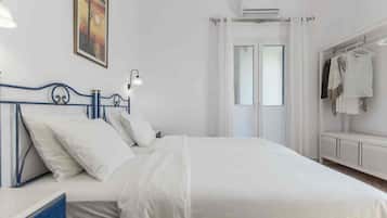 A bedroom with a bed, a bedside table, a hanging light, a wardrobe, and a window with curtains.