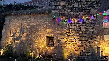 Un bâtiment en pierre doté d’une petite fenêtre et d’une porte, décoré de guirlandes lumineuses colorées.
