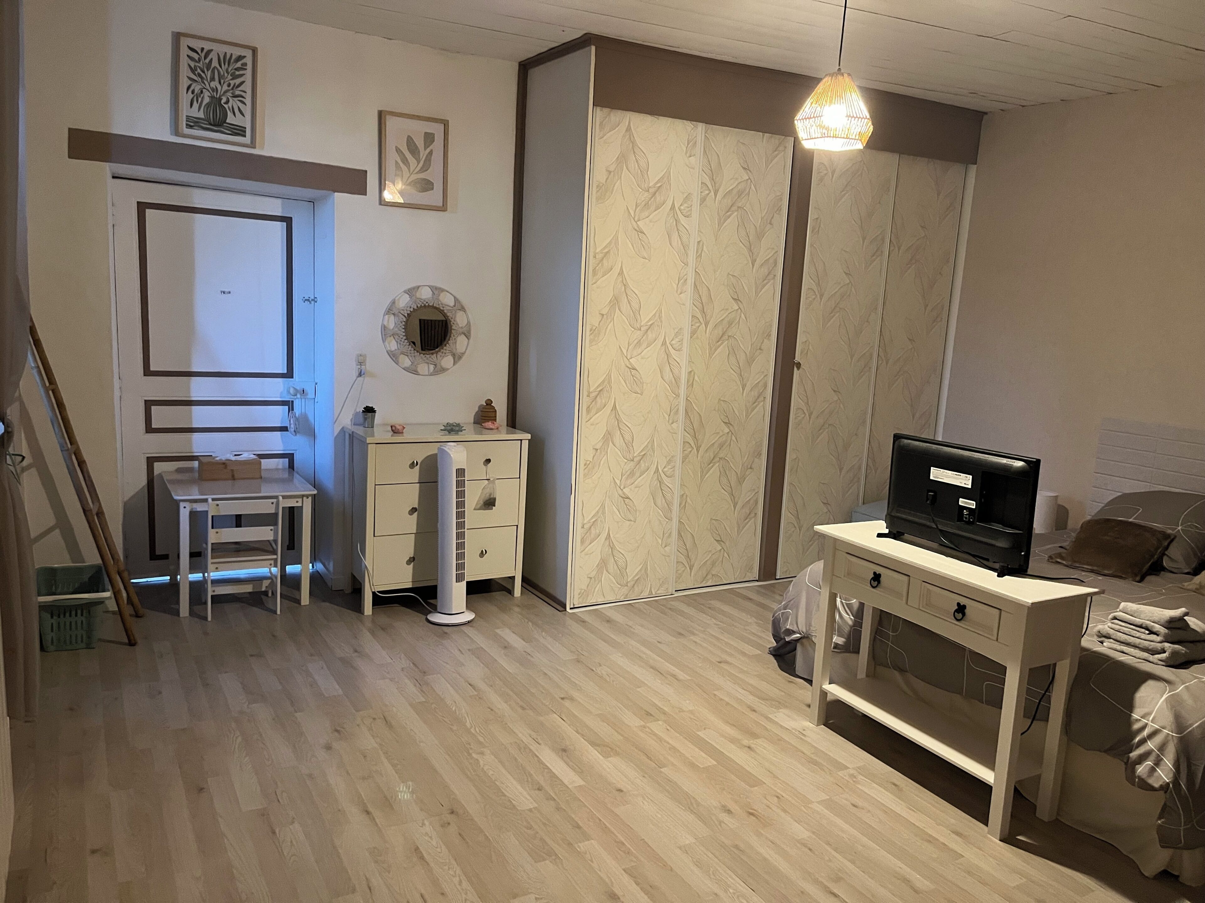 Une chambre à coucher comprenant un lit, un bureau, une chaise, une armoire et un téléviseur.