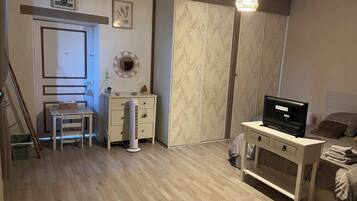 Une chambre à coucher comprenant un lit, un bureau, une chaise, une armoire et un téléviseur.