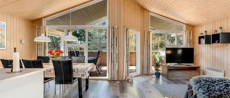 Een ruime woonkamer met een eettafel, stoelen, een bank en een televisie.