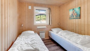 Una habitación con dos camas individuales, una ventana con vistas, un cuadro en la pared y una lámpara en el techo.