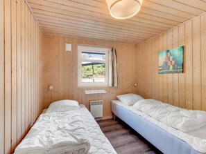 Ein Zimmer mit zwei Einzelbetten, einem Fenster mit Blick, einem Bild an der Wand und einer Deckenleuchte.